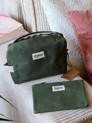 Trousse de toilette verte et pochette assortie sur surface matelassée beige et rose.